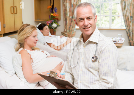 Arzt von schwangeren Frauen halten Diagramm und lächelnd sitzen Stockfoto
