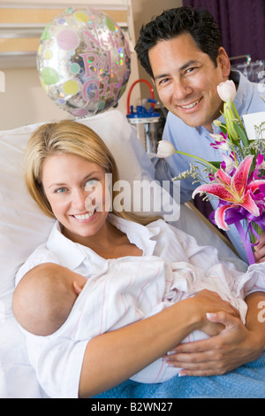 Neue Mutter mit Baby und Mann im Krankenhaus lächelnd Stockfoto