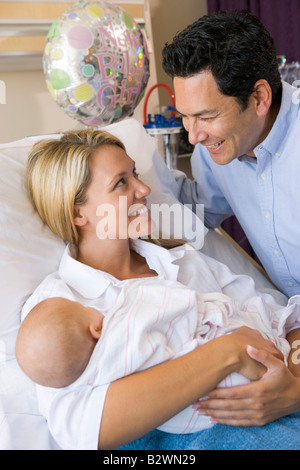 Neue Mutter mit Baby und Mann im Krankenhaus lächelnd Stockfoto