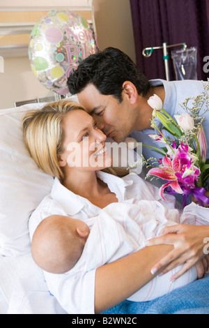 Neue Mutter mit Baby und Mann im Krankenhaus lächelnd Stockfoto