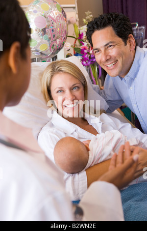 Junge Eltern mit Baby Rücksprache mit Arzt und lächelnd Stockfoto