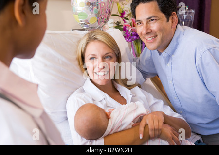 Junge Eltern mit Baby Rücksprache mit Arzt und lächelnd Stockfoto