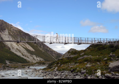 Backpacker kreuzt die Hooker Fluss Drehbrücke in Mt Cook NP in den Südalpen, Canterbury, Südinsel, Neuseeland Stockfoto