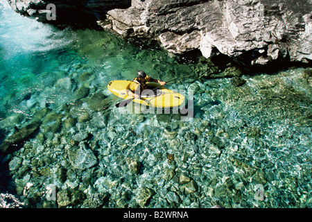 Kajakfahrer in ruhigem Wasser in der Nähe von großen Felsen Stockfoto