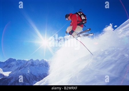 Skifahrer, die springen auf verschneiten Hügel (Lens Flare) Stockfoto