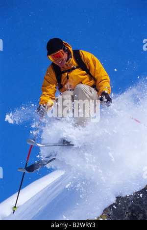 Skifahrer auf verschneiten Hügel springen und lächelnd Stockfoto