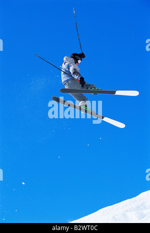 Skifahrer, die dabei auf verschneiten Hügel springen Stockfoto