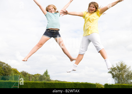 Zwei junge Mädchen springen auf dem Trampolin lächelnd
