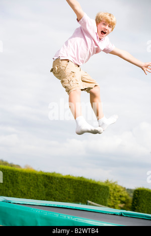 Junge, springen auf dem Trampolin lächelnd Stockfoto