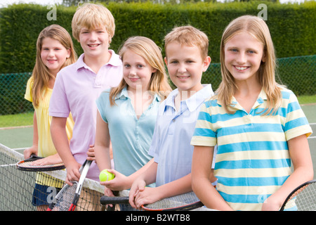 Fünf junge Freunde mit Schlägern auf Tennis Court lächelnd Stockfoto