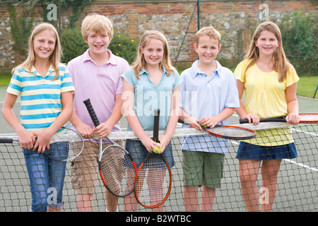 Fünf junge Freunde mit Schlägern auf Tennis Court lächelnd Stockfoto