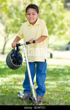 Junge im Freien auf Roller lächelnd Stockfoto