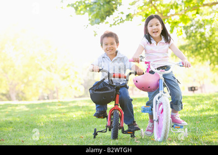 Bruder und Schwester im Freien auf Fahrrädern lächelnd Stockfoto