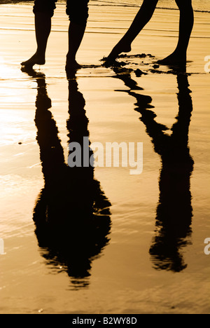 Paar spiegelt sich im nassen Sand am Strand von Bantham Stockfoto