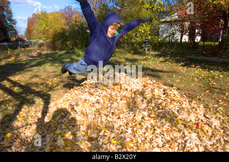 Junge, springen in Haufen Blätter Stockfoto