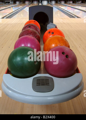 Eine Vielzahl von bunten Bowling-Kugeln sitzen in den Ball zurück auf der Bowlingbahn Stockfoto