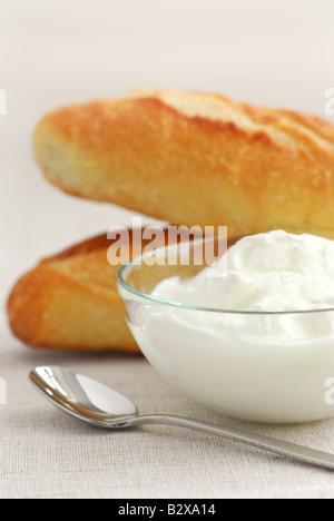 Joghurt in einer klaren Glasschale und Brot serviert Stockfoto