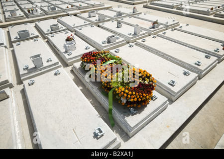 Blumenkränze legen Sie auf eine der mehreren identischen Gräber auf dem Friedhof Cristobal Colon Nekropole in Havanna, Kuba Stockfoto