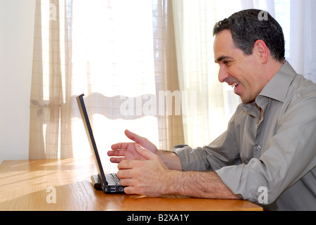 Mann am Schreibtisch sitzt und in seinen Computer zeigen Freude und Aufregung suchen Stockfoto