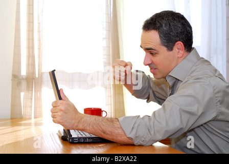 Mann sitzt an einem Schreibtisch Stanzen seinem Computer in der frustration Stockfoto