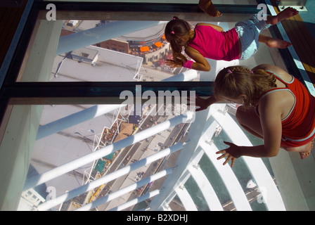 zwei Kinder schauen auf den Boden 100m unter ihnen durch den Glasboden der Spinnaker Tower. Stockfoto