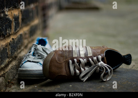 Ungerade Trainer auf dem Bürgersteig verworfen Stockfoto