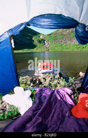 Frau im Freien am Campingplatz mit Zelt Spritzwasser vom Fluss auf Gesicht Stockfoto