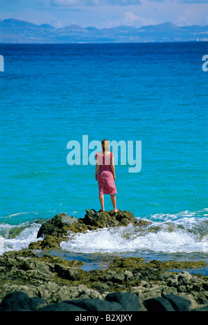 Frau, die im Freien auf den großen Felsen am Meer Stockfoto