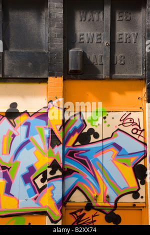 Graffiti auf Arcade von Geschäften unter einem Turm Wohnblock in Margate Kent Stockfoto