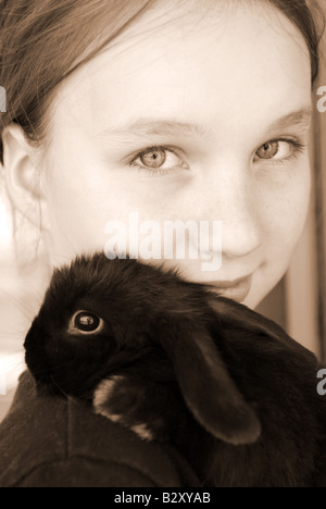 Porträt eines jungen Mädchens hält ein schwarzes Baby-Kaninchen in sepia Stockfoto