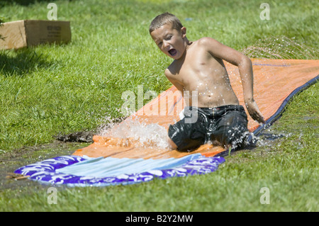 Kleiner Junge gleiten auf einer Wasserrutsche in North Platte, Nebraska an einem sehr heißen Sommertag Stockfoto