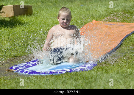 Kleiner Junge gleiten auf einer Wasserrutsche in North Platte, Nebraska an einem sehr heißen Sommertag Stockfoto