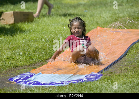 Kleiner Junge gleiten auf einer Wasserrutsche in North Platte, Nebraska an einem sehr heißen Sommertag Stockfoto