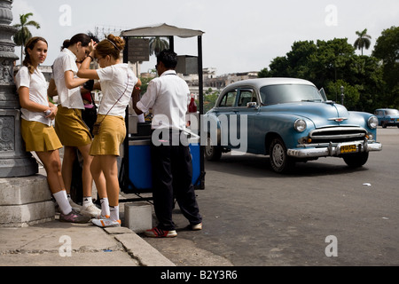 Teenage-Mädchen in Schuluniformen kaufen kalte Leckereien gemacht von zerstoßenem Eis und süßen Sirup in Havanna, Kuba Stockfoto