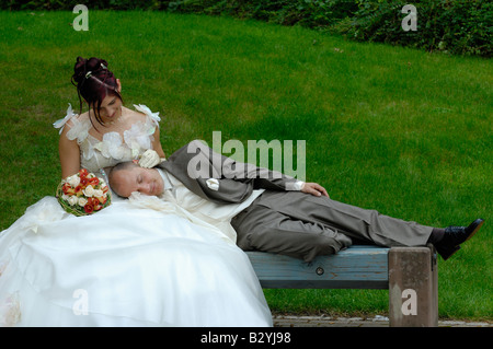 Brautpaar mit Mann schlafend auf seiner Frau in der Bank Park, Frankreich Stockfoto