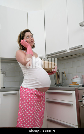 Schwangere Frau Backen in der Küche mit Handy Stockfoto