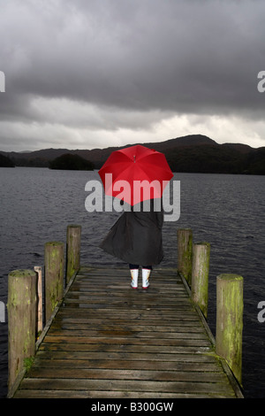 Mädchen am Dock in Regen, Lake Windermere, Cumbria, England Stockfoto