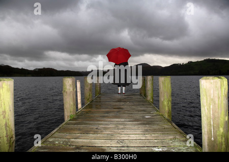 Mädchen am Dock in Regen, Lake Windermere, Cumbria, England Stockfoto