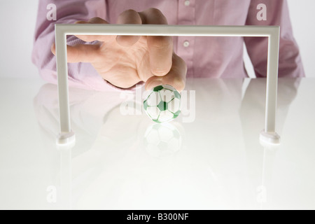 Geschäftsmann mit Miniatur-Fußball spielen Stockfoto