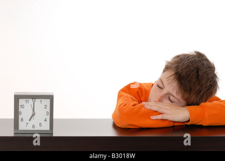 Jungen schlafen neben Wecker Stockfoto