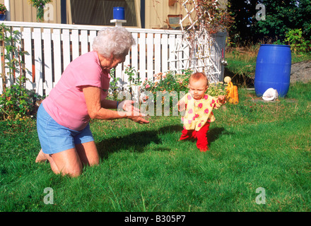 Großmutter und Enkelin zu Hause im Garten Rasen mit weißen Lattenzaun Stockfoto