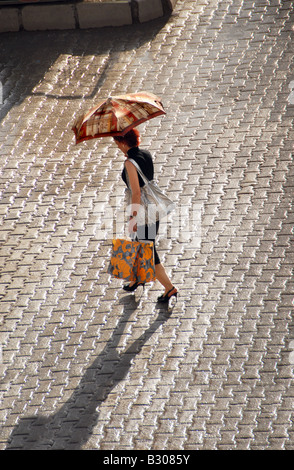 Frau, überqueren eine Kreuzung mit einem Regenschirm nach einer Dusche Stockfoto