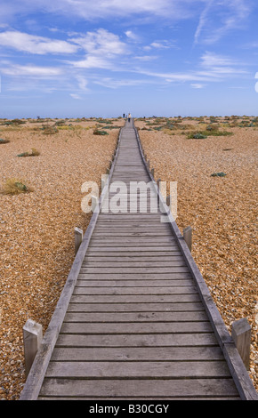 Holzsteg erstreckt sich in die Ferne über den Kiesstrand bei Dungeness in Kent an einem sonnigen Tag Stockfoto