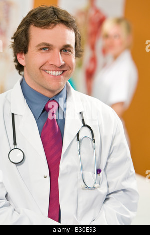 Ein männliche Berater lächelt mit eine Krankenschwester steht im Hintergrund unscharf Stockfoto