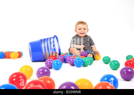 Kleiner Junge sitzt zwischen den farbigen Kugeln Stockfoto