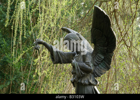 Engel Skulptur gesehen von der Seite, die eine rose Blume in ihrer erhobenen rechten hand Stockfoto
