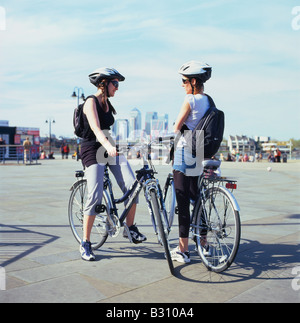 Junge Frauen Radfahrer in Greenwich mit Canary Wharf in der Ferne London England UK KATHY DEWITT Stockfoto