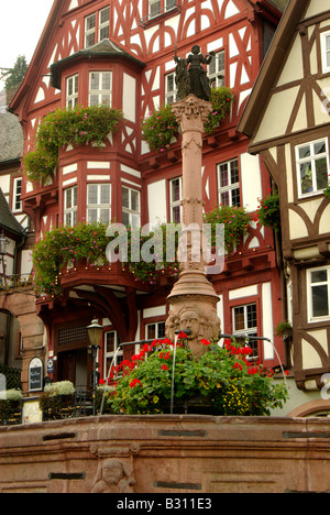 Renaissance-Brunnen mit Blumen und Fachwerkhaus befindet sich auf dem Marktplatz in Miltenberg, Deutschland Stockfoto