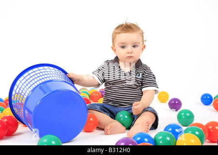 Kleiner Junge sitzt zwischen den farbigen Kugeln Stockfoto