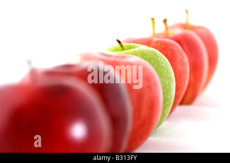 Ein grüner Apfel ist der Eindringling in einer Reihe von rot Stockfoto